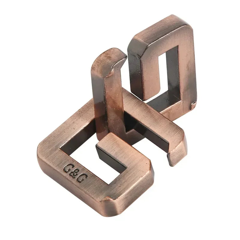 Metal interlocking G-shaped puzzle variant with 'G&G' engraving on a white background