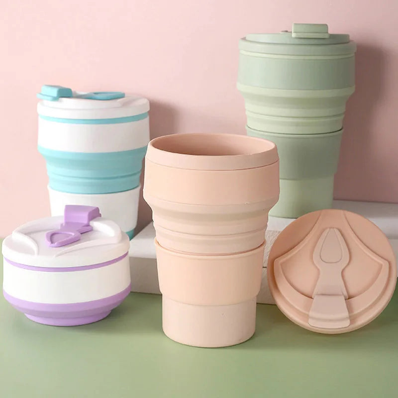 Set of colorful collapsible travel cups on a pink and green background