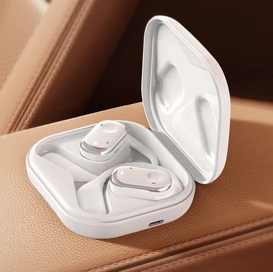 White wireless earbuds in a charging case on a brown leather surface