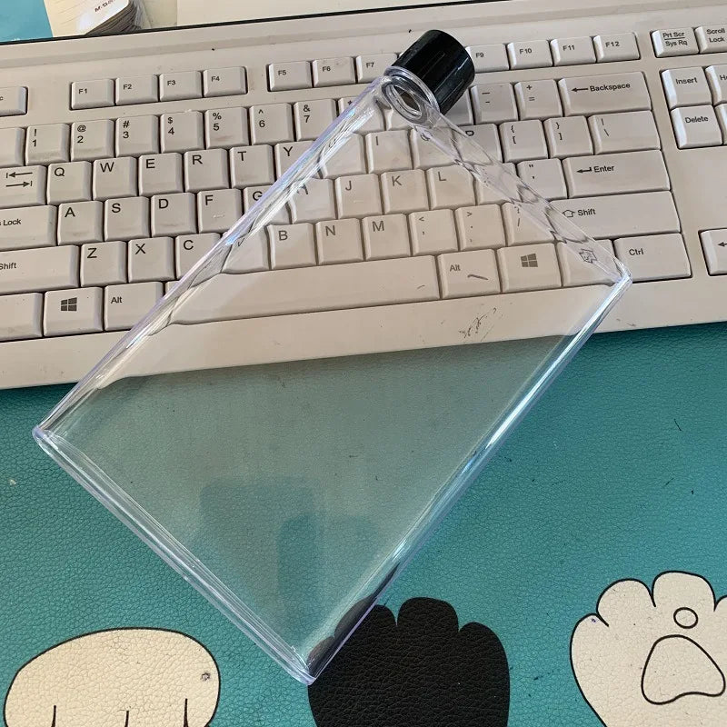 Clear plastic triangle with black cap on a desk with a keyboard in the background