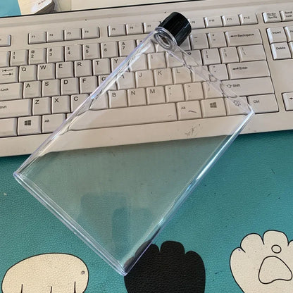 Clear plastic triangle with black cap on a desk with a keyboard in the background