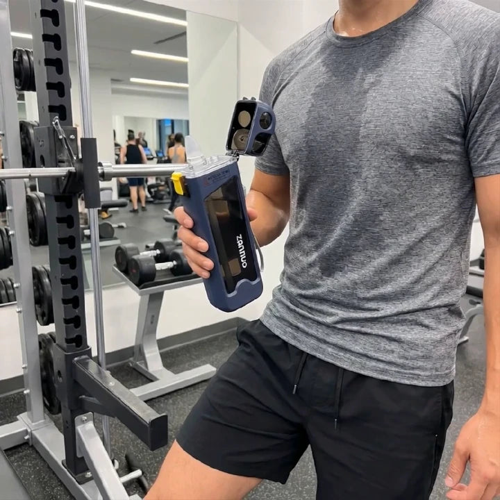 Person holding a rectangular sports water bottle in a gym setting