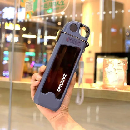 Hand holding a blue square water bottle in front of a store window.