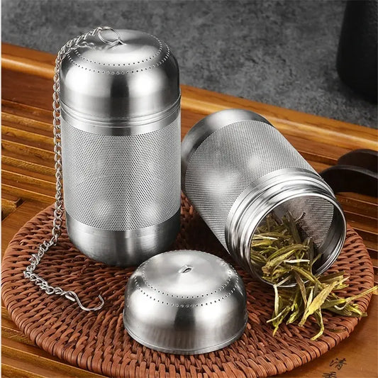 Stainless steel tea infuser with mesh lid on a woven coaster