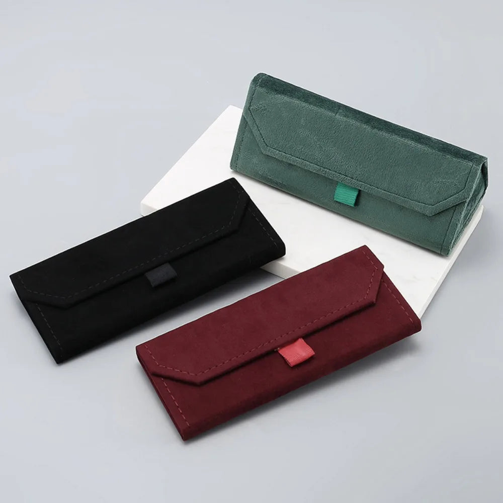 Three faux leather glasses cases in black, red, and green on a light gray background