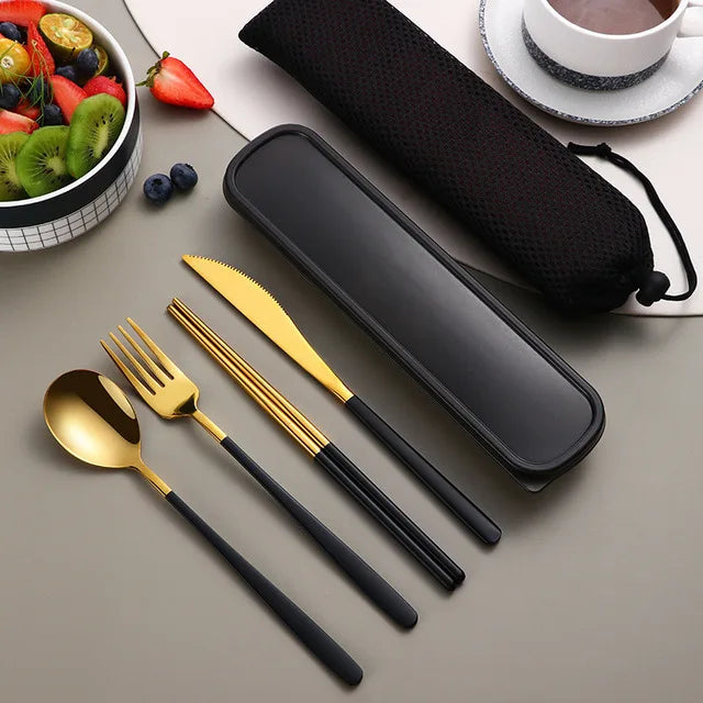 Gold cutlery set with black handles on a gray surface, next to a black carrying case.