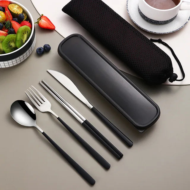 Black travel cutlery set with case on a table with fruits and a cup of tea.