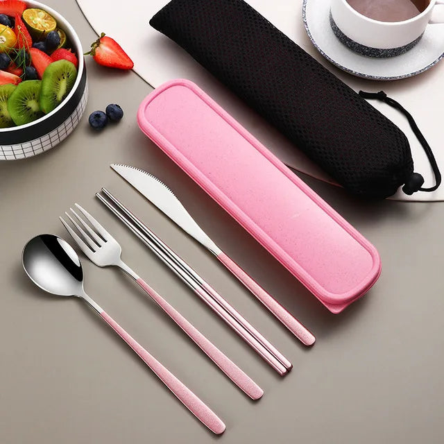 Pink travel cutlery set with case on a table with fruits and tea.