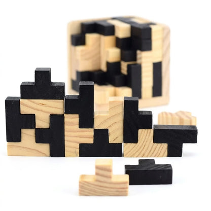 Wooden block puzzle pieces in black and natural light wood, arranged on a white background with a blurred, partially assembled cube in the background.